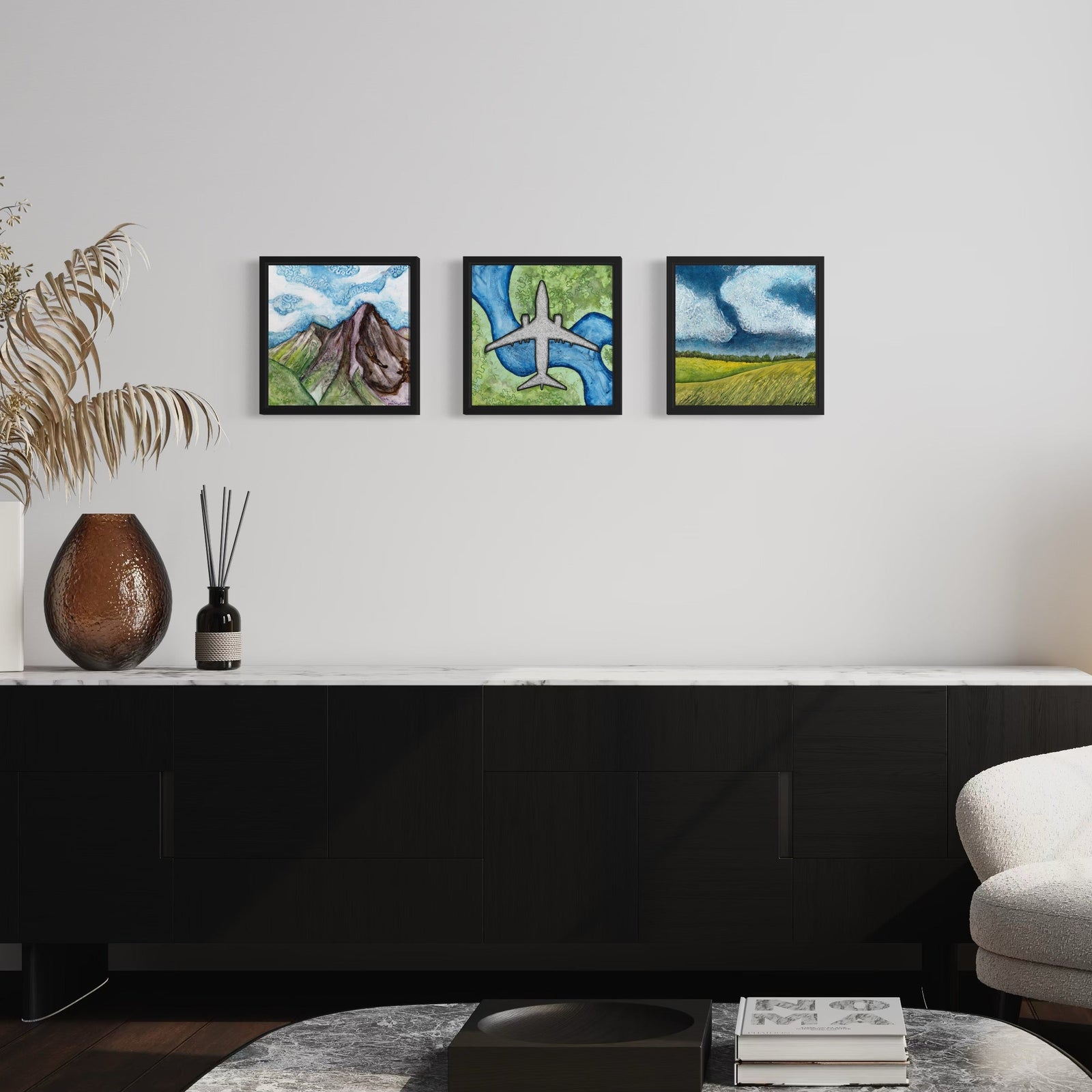 Three framed landscape and airplane paintings by MK Mason hanging on a white wall in a modern living room interior
