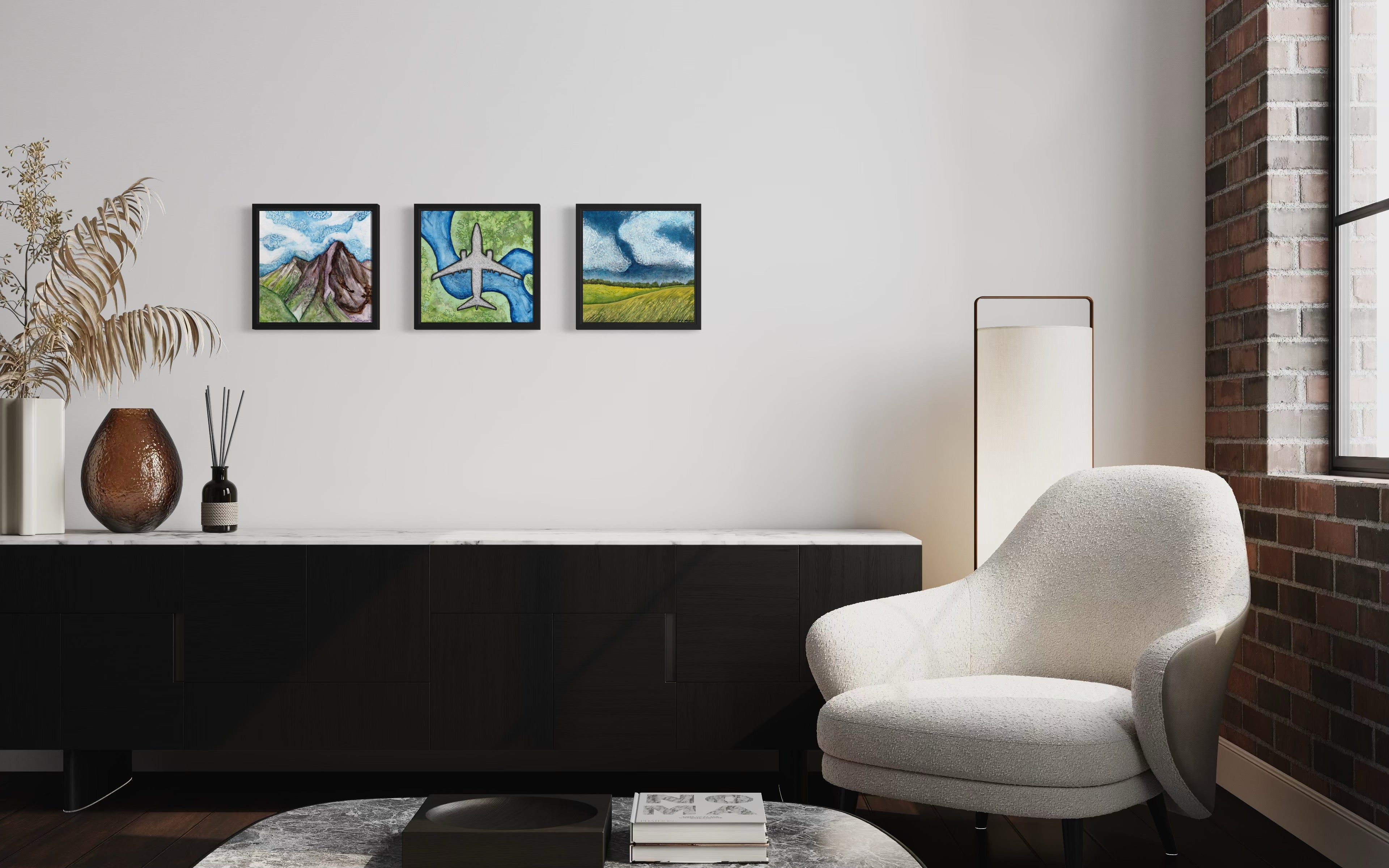 Three framed landscape and airplane paintings by MK Mason hanging on a white wall in a modern living room interior