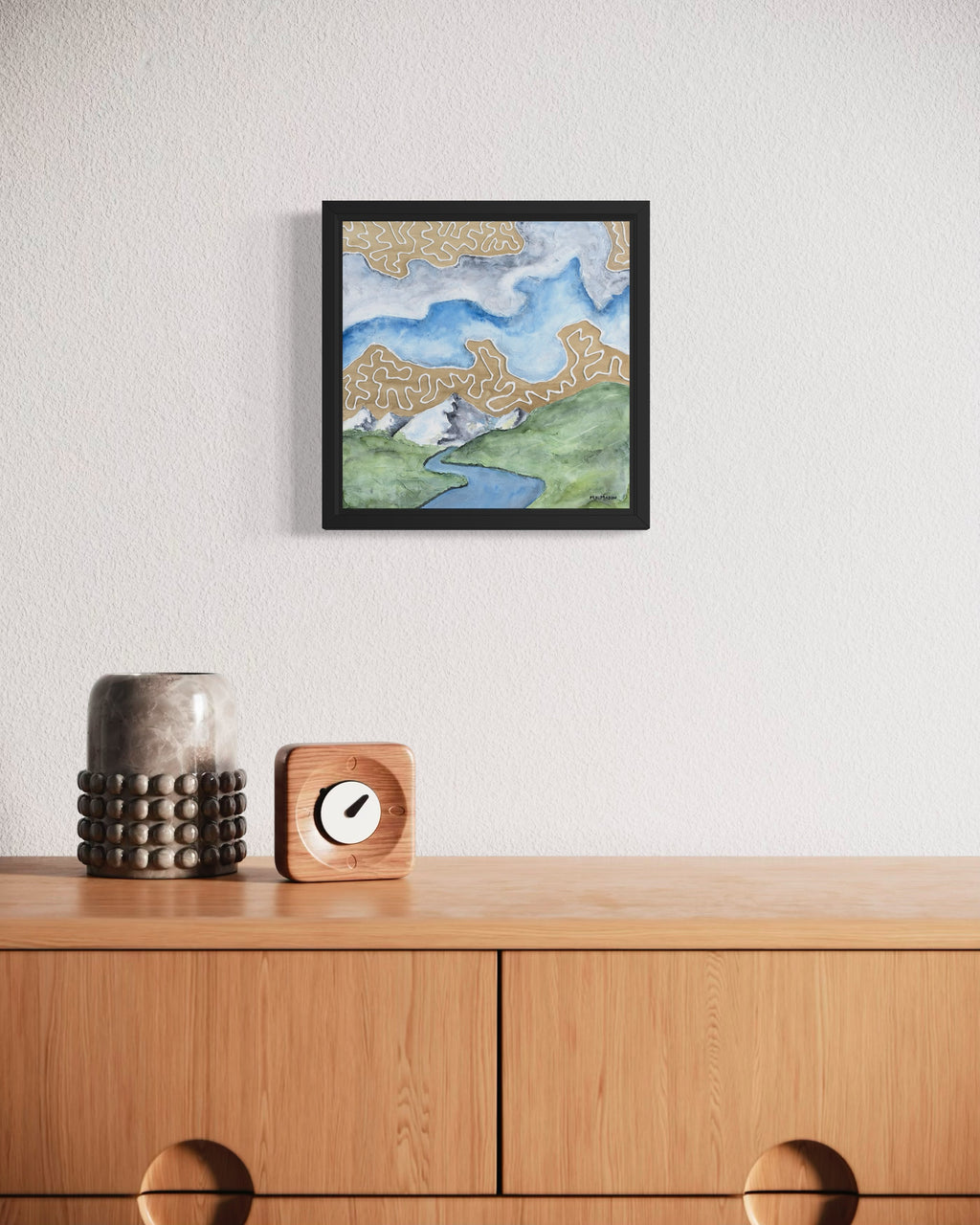 Watercolor landscape with green hills, snowy mountains, a winding blue river, and tan abstract cloud patterns, artwork by MK Mason, interior mockup